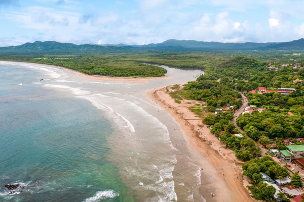 Aerial view of Tamarindo Beach in Guanacaste Province, Costa Rica, showcasing the coastline, lush green forests, and tranquil waters.