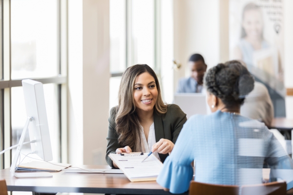 A lawyer helps a client reapply for a residency application, reviewing documents in a professional office setting.