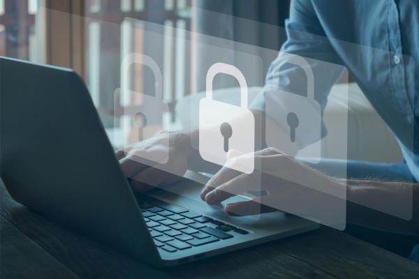 Person working on laptop with transparent floating padlock icons, representing digital security and data protection in modern workplace