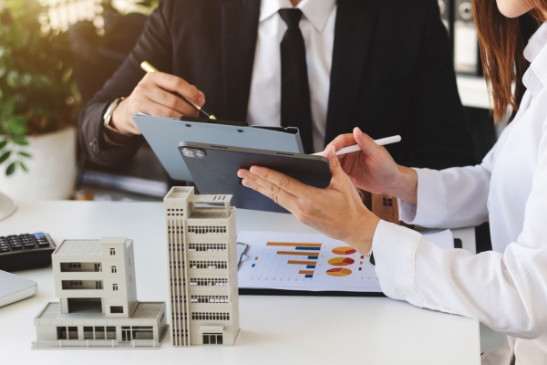 Business professionals analyzing investment data with architectural models of commercial buildings for Free Trade Zone development